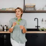 Smiling woman with vegetables in stylish modern kitchen
