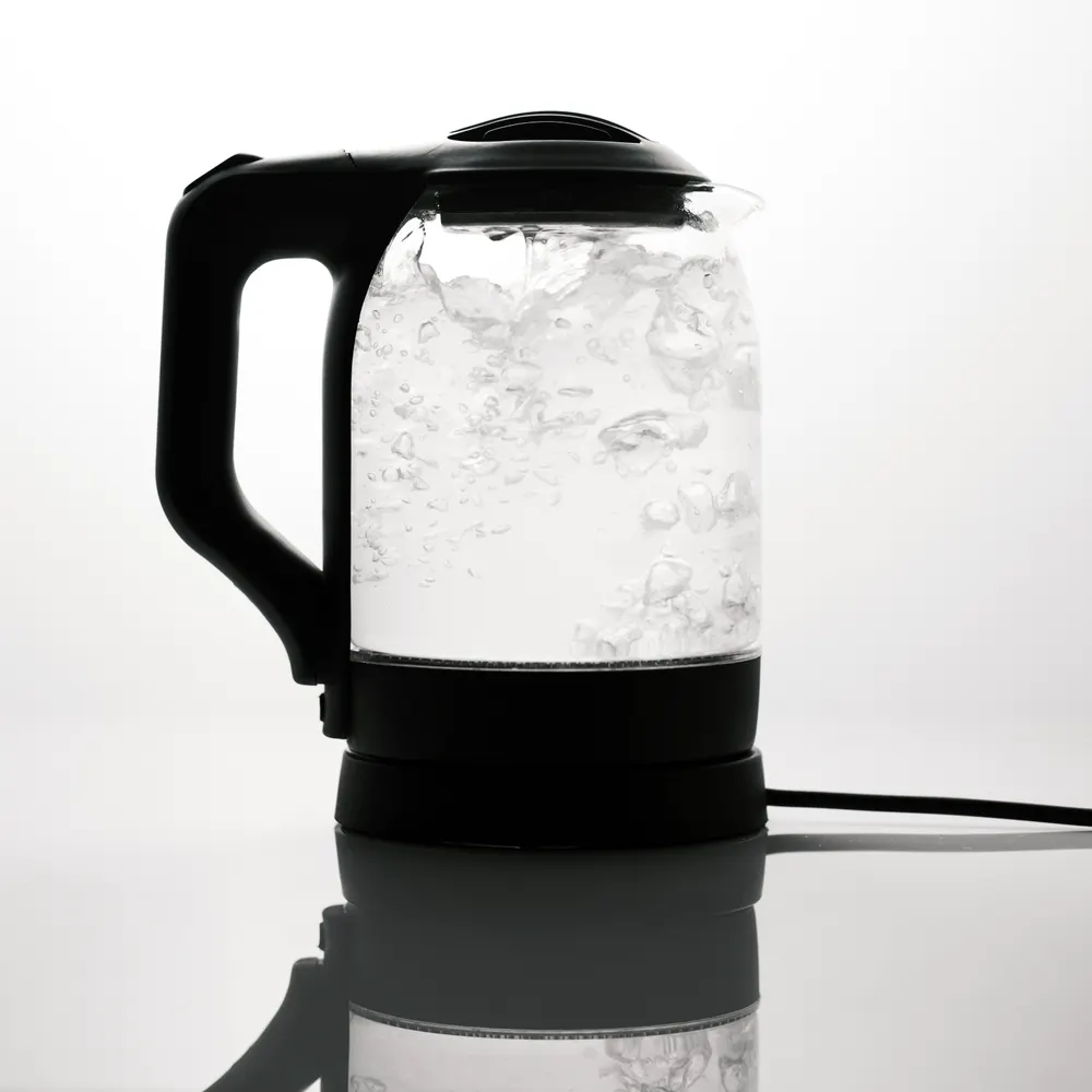 Sleek electric glass kettle boiling water on reflective surface