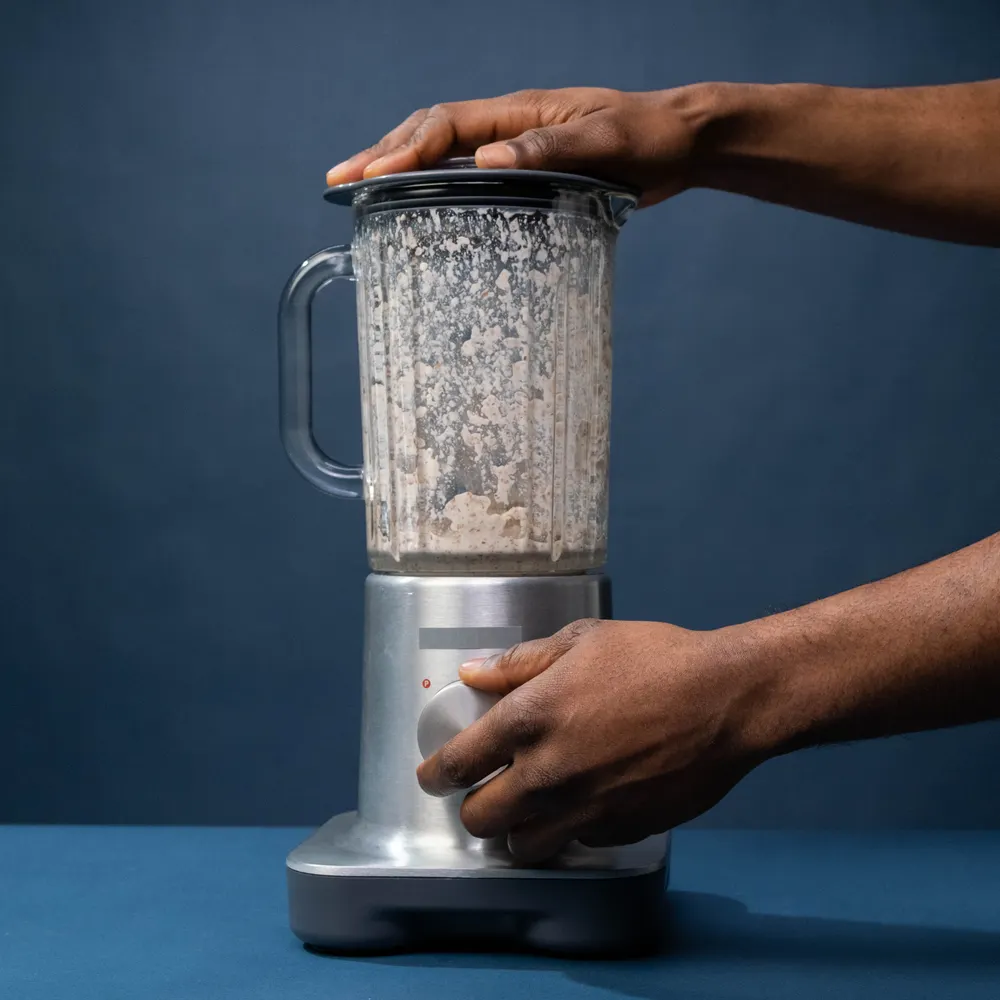 Close-up of male hands operating a blender in kitchen setting