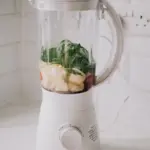 Blender filled with bananas and spinach ready for smoothie