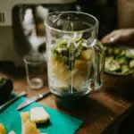 Blender with kiwi and pineapple chunks ready to make smoothie