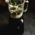 Close-up of blender with fresh green smoothie ingredients in kitchen